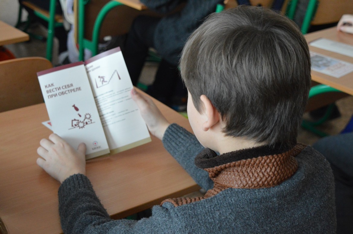 A school boy reading what to do in case of shelling, February 2018