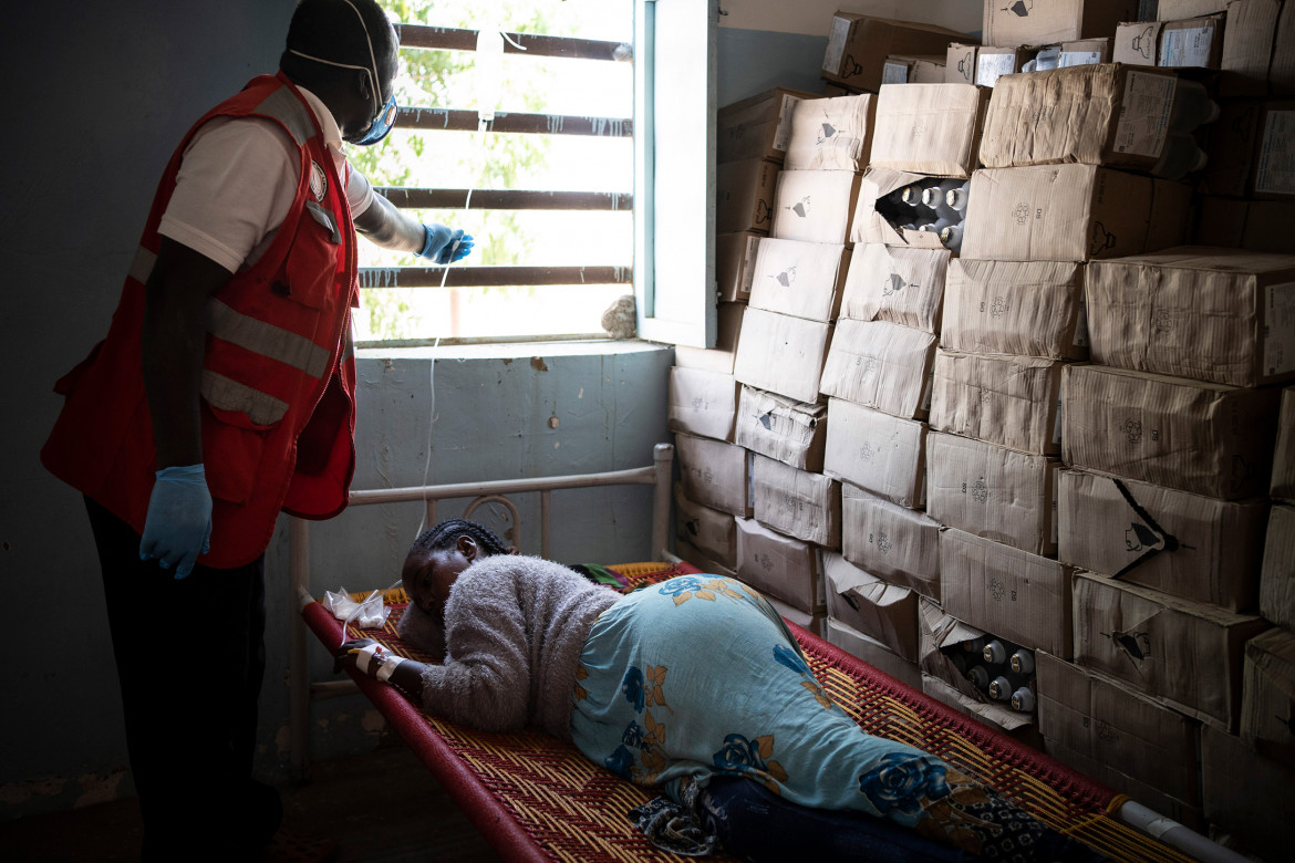 السودان - مخيم الحميدية للاجئين، موظف رعاية صحية في جمعية الهلال الأحمر السوداني يعالج امرأة إثيوبية فرت من القتال في تيغراي ووصلت لتوها إلى المخيم.