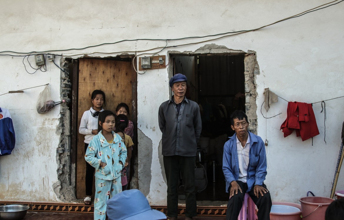 Locals of Laukkhaing community look on as their family members and neighbours collect blankets and mattresses.