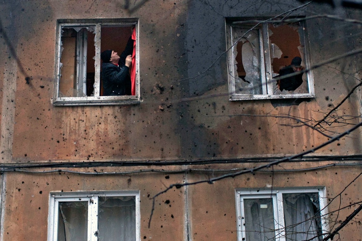 Donetsk, Ukraine, January 2015. A man tries to repair a shell-damaged window in his apartment.