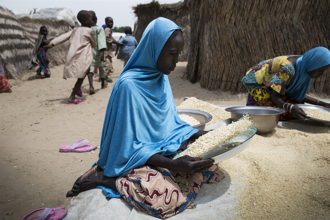 Borno State, Nigeria. A woman sifts maize in a camp where people have sought refuge from fighting, September 2019. C.A. Wells / ICRC