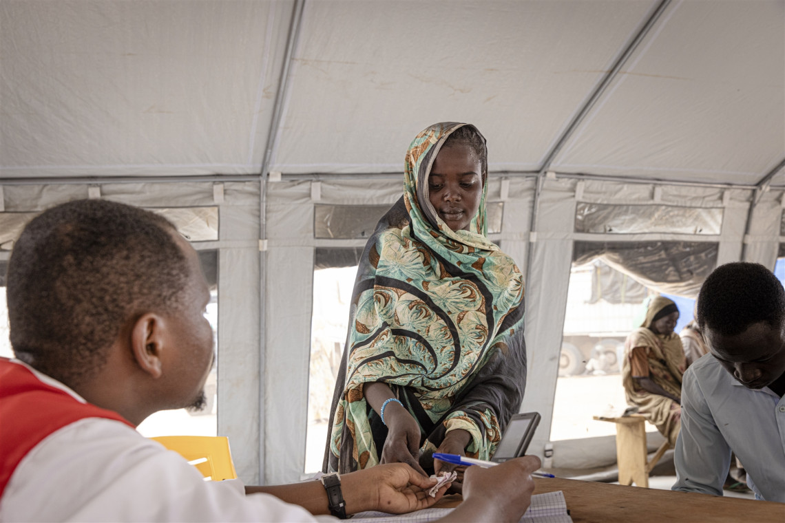 祖哈尔正在把一张写有她叔叔电话号码的纸条交给红十字会志愿者。她使用红十字电话服务联系住在苏丹东部加达里夫的叔叔，希望能去投靠他生活，但电话始终没有接通。
