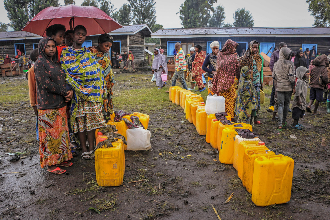 Province du Nord-Kivu. Des personnes déplacées ont trouvé refuge dans une école d'un petit village proche de Goma. Des jeunes filles attendent leur tour lors d'une distribution d'eau potable du CICR.