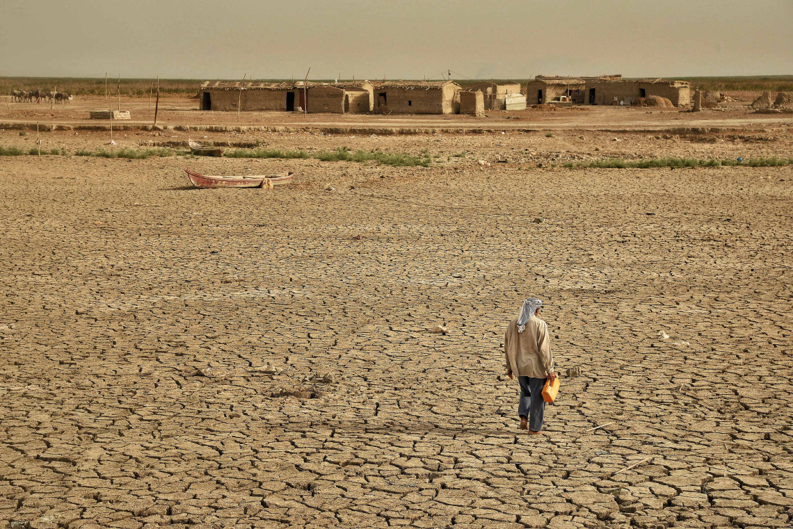 Un hombre camina hasta lo que queda de las marismas para recoger papiros y cañas con los que alimentar a su rebaño después de una sequía que afectó a la aldea entera. 