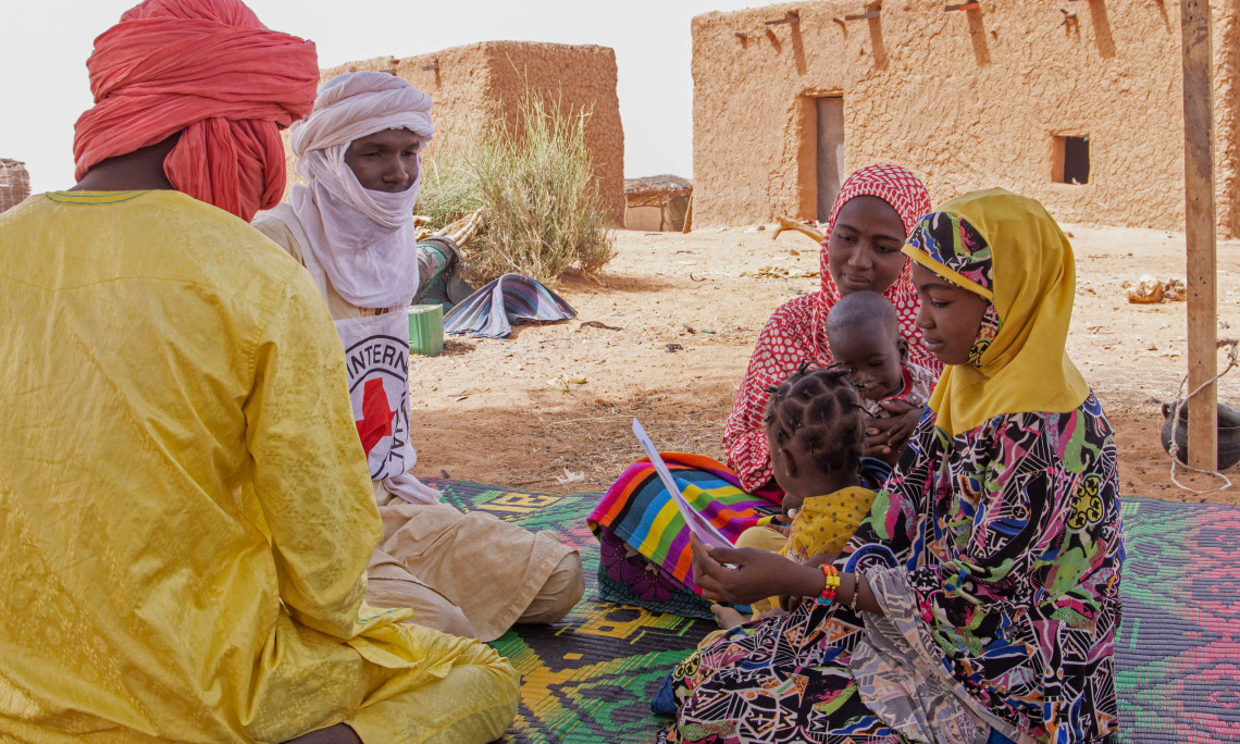 Dans un village près de Ménaka, au Mali. Amina (écharpe jaune), qui a fui la violence armée dans un pays voisin, discute avec des collaborateurs du CICR. Les informations fournies ont permis de retrouver sa tante et de rétablir le contact avec sa famille.