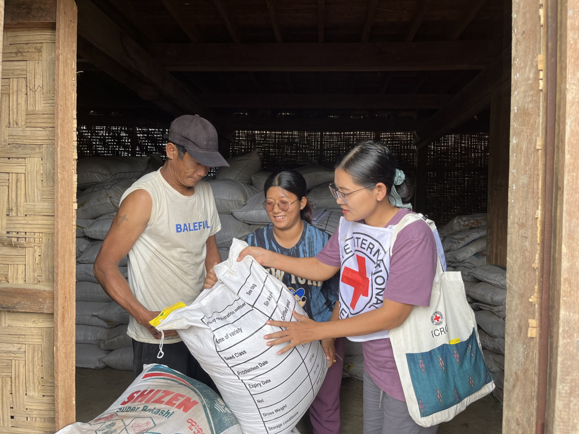 克钦邦密支那办事处的一名红十字国际委员会工作人员向当地农民派发水稻种子。