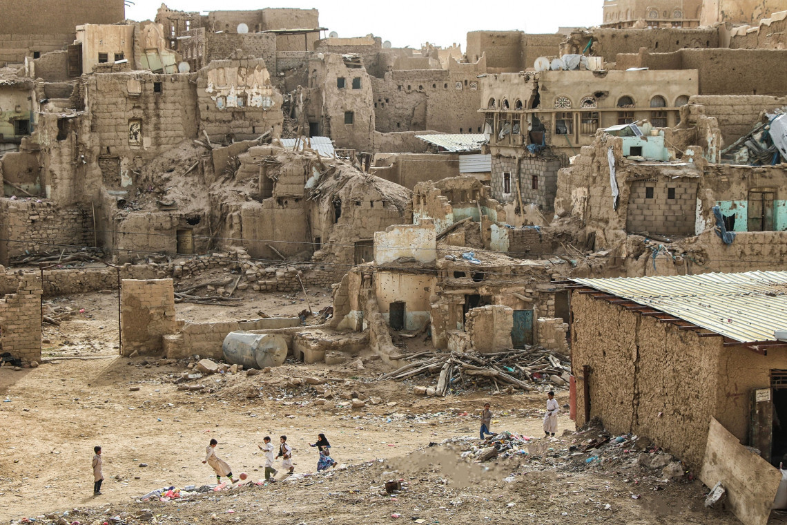 Sa’ada, Yemen. Children play football against a backdrop of destroyed houses, 2019.